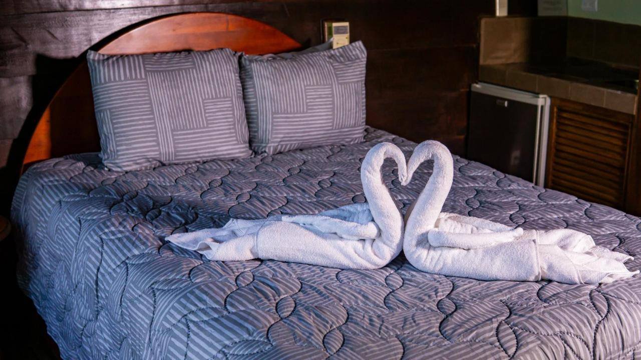 La Fortuna Waterfall Bungalows: double bed with a towel swan and a wooden headboard