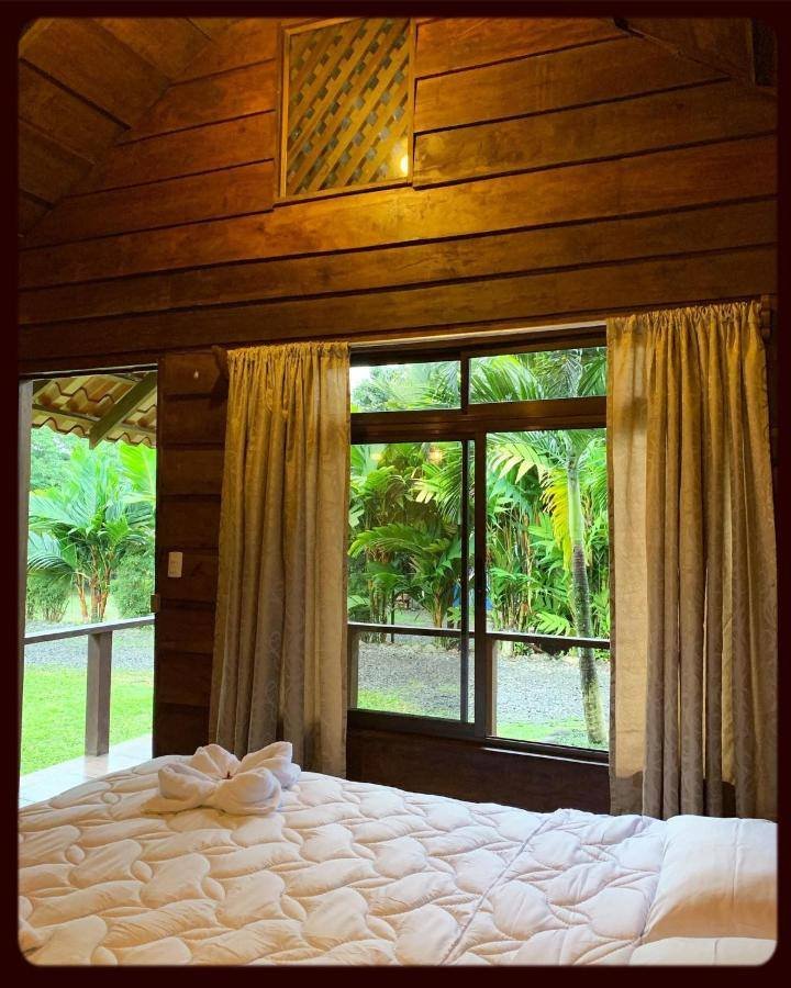 La Fortuna Waterfall Bungalows: wood-paneled bedroom with a large window onto the garden